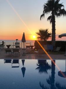 a swimming pool with a sunset in the background at Hotel Albatros in Ischia