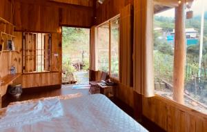 um quarto com uma cama e uma grande janela em A Phủ Home’s em Bắc Yên