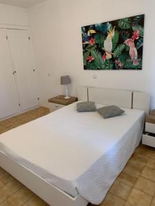 a white bed in a room with a painting on the wall at Squash Club Apartamentos in Portimão
