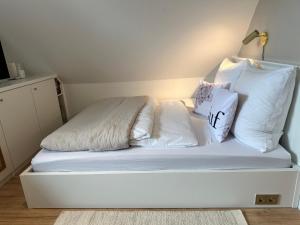 Una cama con sábanas blancas y almohadas. en lóuf en Wiesmoor