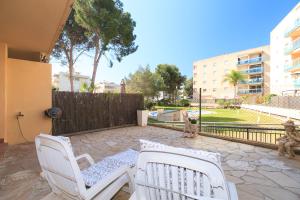 a patio with two white chairs and a fence at UHC Golden Pineda Apartments in Salou