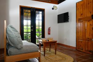 ein Wohnzimmer mit einem Stuhl, einem Tisch und einem TV in der Unterkunft The Cottages - Unit 2 in Soufrière