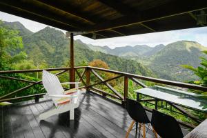 a balcony with chairs and a table and mountains at The Cottages - Unit 2 in Soufrière
