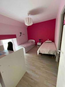 a bedroom with a bed and a pink wall at Longère au coeur du vignoble de Champagne in Lachy