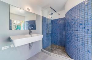 a bathroom with a sink and a shower with blue tiles at The Beach House Bonaire in Kralendijk +9 photos