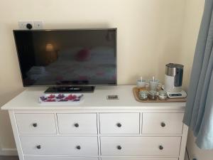 a white dresser with a flat screen tv on top of it at Wellington view One en suite shower and super king bed in Wellington