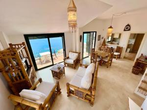 una sala de estar con sillas de madera y vistas al océano. en Chalet Tropical Bay Views, en La Herradura