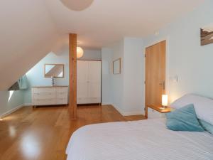 a white bedroom with a bed and a dresser at Number 10 The Penthouse in Swanage