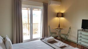 a bedroom with a bed and a window with a balcony at Quinta do Outono in Armamar