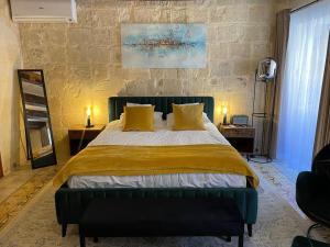 a bedroom with a large bed with yellow pillows at Babel Suites in Valletta