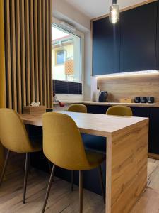 a dining room with a wooden table and yellow chairs at Apartament Sanok nad stawami in Sanok