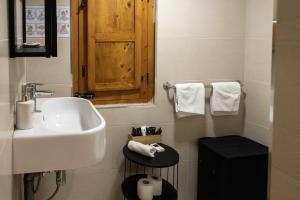 a white bathroom with a sink and a wooden cabinet at Babel Suites in Valletta