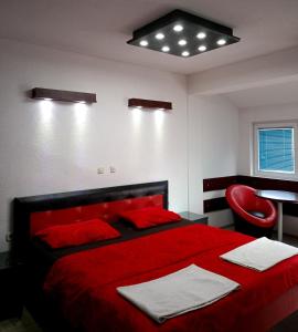 a bedroom with a red bed and a red chair at Kice Apartments in Ohrid
