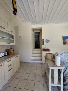 a kitchen with white cabinets and a tile floor at Palaiokrassa sunny appartment in Andros
