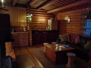 a living room with a couch and a table in a kitchen at Pattoinlampi Saunamökki 