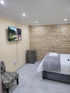 1 dormitorio con 1 cama y TV en la pared en MIRAJO Guest House, en Ciudad del Cabo