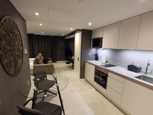 a kitchen and living room with a counter and chairs at BRAND NEW - Studio Apartments in EuroCity - Pool - Rock View - Balcony - Free Parking - Holiday and Short Let Apartments in Gibraltar in Gibraltar