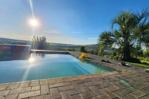 a large swimming pool with the sun in the background at RaHa Soul Sanctuary - Entire Home in De Deur