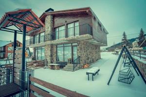 a house in the snow with a bench in front of it at Cottage Panorama in Bakuriani