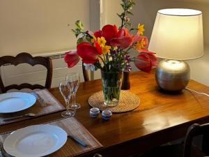 einen Tisch mit einer Vase aus Blumen und einer Lampe in der Unterkunft Cottage Vesqueville in La Hoguette