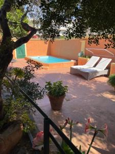 un patio con piscina y tumbonas en Villa ANTONIA en Calvi