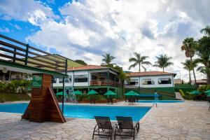a resort with a swimming pool with chairs and a building at Hotel Fazenda Vale Amanhecer in Igarapé