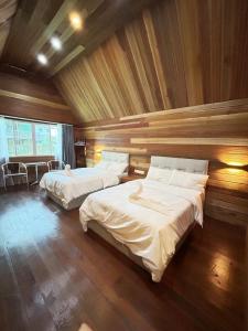 2 camas en una habitación con paredes de madera en 仙本那中梁度假庄园 ZhongLiang Holiday Garden Semporna en Semporna