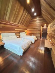 2 camas en una habitación con paredes de madera en 仙本那中梁度假庄园 ZhongLiang Holiday Garden Semporna en Semporna