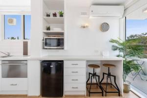 a kitchen with white cabinets and a black refrigerator and stools at South Yarra apartment with stunning views in Melbourne