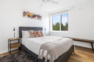 a white bedroom with a large bed and a window at South Yarra apartment with stunning views in Melbourne