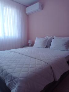 1 cama blanca grande en un dormitorio con ventana en Apartament Lili Sozopol, en Sozopol