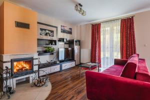 Dom Zaskalskie 10b في غاوركي: غرفة معيشة مع أريكة حمراء ومدفأة