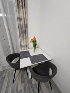 un tavolo bianco con due sedie e un vaso con fiori di Orchidea3 a Finkenstein am Faaker See