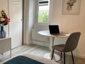 a room with a table with a laptop on it at AUX 4 LOGIS Appart-hotel - Studio Le Flore - Petit déjeuner inclus 1ère nuit in Foix +16 photos