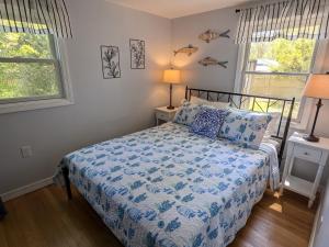 a bedroom with a bed with a blue comforter and two windows at Spacious 4BR house on a quiet street in Centerville 5 min to Craigville beach in Centerville