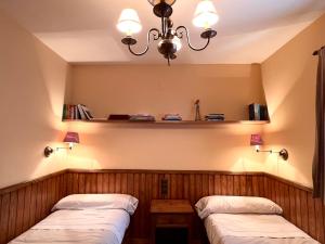 Habitación con 2 camas y lámpara de araña. en Apartament de la Vall Ferrera, en Àreu