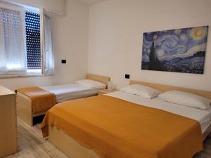 a bedroom with two beds and a painting on the wall at Alberto Quadrilocale a soli 150m dal mare in Marina di Castagneto Carducci