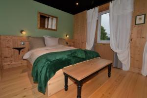 ein Schlafzimmer mit einem Bett mit einer grünen Decke darauf in der Unterkunft Chambres d'hôtes La Carrée in Les Fins