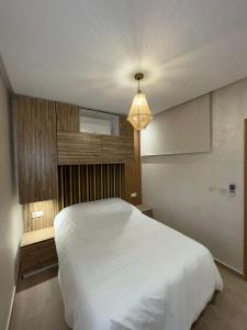 - une chambre avec un lit blanc et une lampe pendant dans l'établissement 4 Flowers, à Marrakech