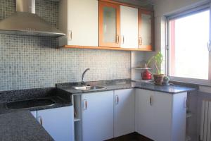 a kitchen with white cabinets and a sink and a window at Apartamento Lugo Centro in Lugo