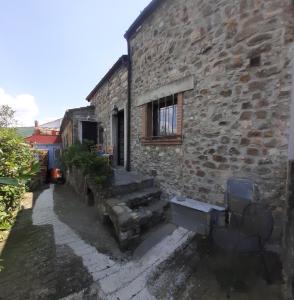 ein Steinhaus mit zwei Bänken und einem Fenster in der Unterkunft Montedivalli in Montedivalli Chiesa