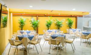 una habitación con mesas y sillas y una pared amarilla en Hotel Regency Suites La Feria, en Bogotá