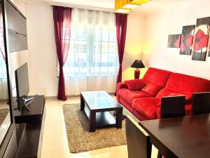 a living room with a red couch and a table at Apartamento Praia Naval in Isla de Arosa