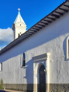eine weiße Kirche mit einem Kirchturm und einer Tür in der Unterkunft Hotel Casa Merced in Cuenca