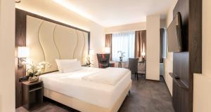 ein Hotelzimmer mit einem großen weißen Bett und einem Schreibtisch in der Unterkunft PLAZA INN Mannheim in Mannheim + 80 Fotos