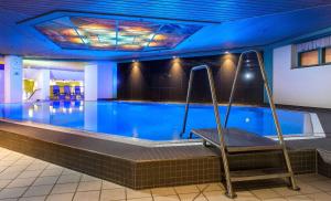 a large swimming pool with a swing in a building at Maritim Hotel Magdeburg in Magdeburg