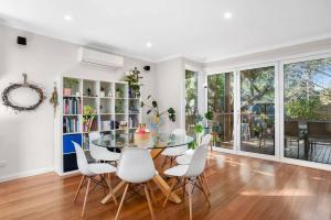 a dining room with a glass table and white chairs at Explore Frankston South from this lovely home in Frankston