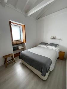 een witte slaapkamer met een groot bed en een raam bij Casa do Porto in Madalena