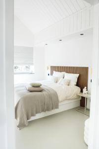 a white bedroom with a large bed with white walls at Stijlvol huisje in de Brabantse natuur! Tuynloodz B in Beers