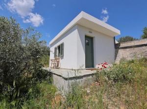 a small white house with a chair on the porch at Little house in the olive grove in Melissátika